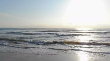 Sunrise Beach. Hızlı hareket kamera sahilde. Sahilde araba taklit. Güneşin arkasında deniz dalga kıyıya yaklaşıyor. Güneş su yansıması.