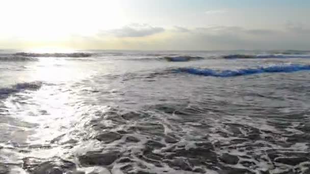 Φωτογραφική μηχανή κίνηση μπροστά από τα κύματα της θάλασσας. Ο ήλιος το πρωί, λάμπει στη φωτογραφική μηχανή και αντικατοπτρίζεται στο νερό. Έπεσε σε ανάλυση 4k — Αρχείο Βίντεο