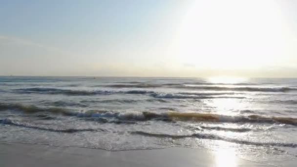 Amanecer en la playa. Cámara de movimiento rápido en la playa. Imitación del coche en la playa. La ola del mar en la parte posterior del sol se acerca a la orilla. El reflejo del sol en el agua . — Vídeos de Stock
