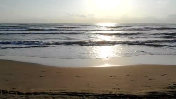 Amanecer en la playa. Cámara de movimiento rápido en la playa. Imitación del coche en la playa. La ola del mar en la parte posterior del sol se acerca a la orilla. El reflejo del sol en el agua . — Vídeos de Stock