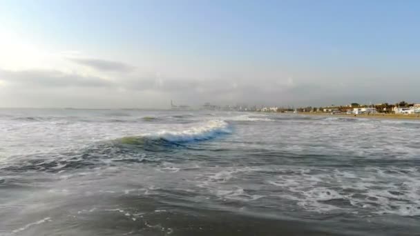 Kamerarörelserna framför havet vågorna. Morgonsolen skiner i kameran och återspeglas i vattnet. Sjunkit till 4k — Stockvideo