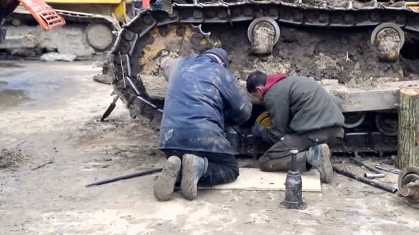 Працівник ремонтує бульдозера. Ремонт важкого будівельного обладнання на будівельному майданчику — стокове відео