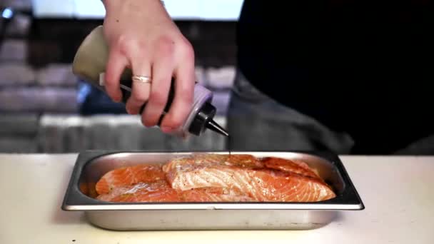 Cocine regando especias aromáticas de pescado rojo y aceite. Prepara el pescado para hornear. Pescado rojo marino — Vídeo de stock