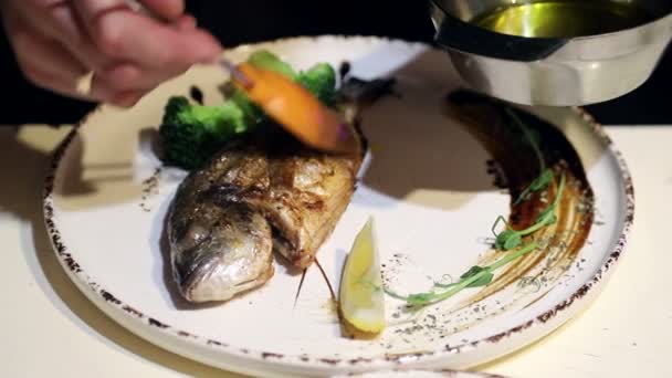 Pesce dorado su un piatto. Piatto di firma di chef su un piatto con limone ed erbe aromatiche — Video Stock