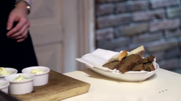 El camarero en los guantes de pone el pan en el plato, y lo prepara para la entrega . — Vídeo de stock