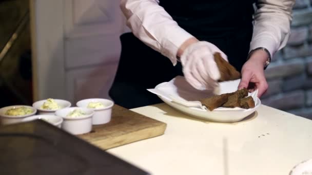 El camarero en los guantes de pone el pan en el plato, y lo prepara para la entrega . — Vídeos de Stock