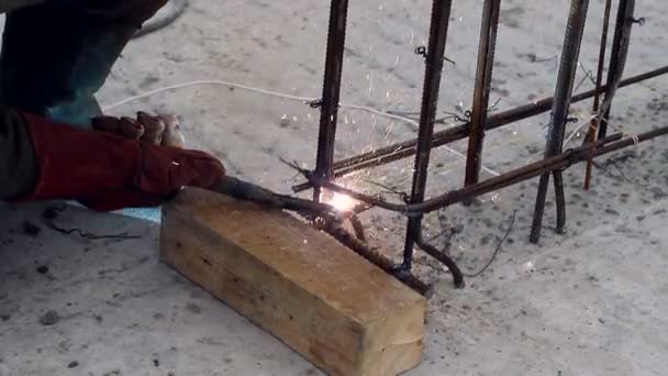 En anställd svetsar en metall struktur på en byggarbetsplats. Bygg-och anläggningsarbeten. Arbete utomhus — Stockvideo