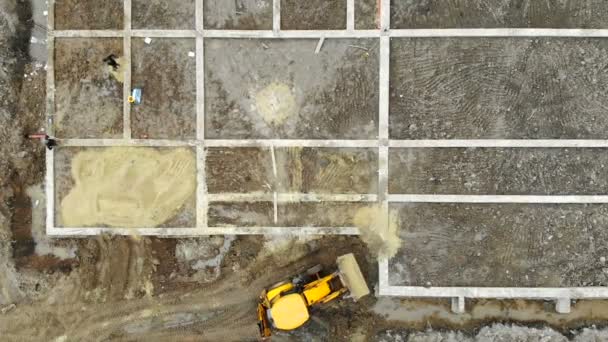 Vue aérienne sur les fondations du bâtiment supérieur. La pelle apporte du sable pour la fondation de la maison — Video