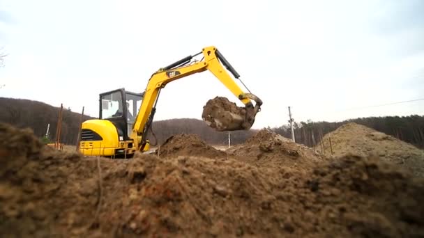 Movimiento lento de una excavadora cavando un hoyo y arrojando tierra. Primer plano de un cubo de excavadora que arroja la tierra. Disparo con lente gran angular — Vídeos de Stock