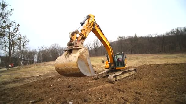 Gros plan d'un godet d'excavatrice qui jette la terre. Mouvement lent d'une pelleteuse creusant une fosse et jetant de la saleté. Tourné par objectif grand angle — Video