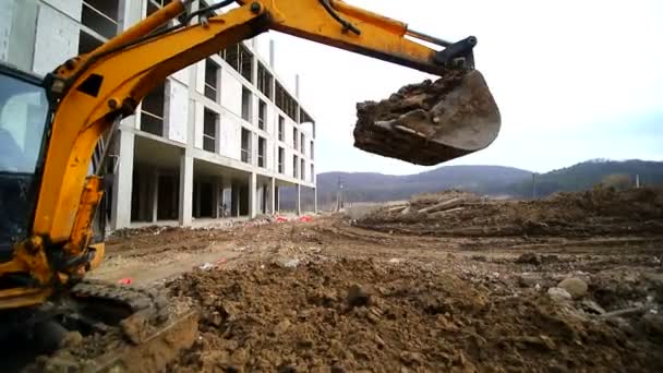 Movimento lento de um escavador cavando um poço e jogando sujeira. Close-up de um balde de escavadeira que joga fora a terra. Filmado por lente de grande ângulo — Vídeo de Stock