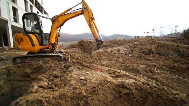 Movimiento lento de una excavadora cavando un hoyo y arrojando tierra. Primer plano de un cubo de excavadora que arroja la tierra. Disparo con lente gran angular — Vídeos de Stock