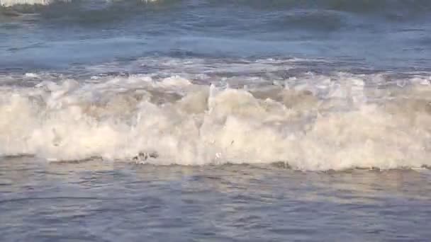 波は水に太陽が輝いて、海岸の近くに来ない。海の波は、白い砂浜の美しい海岸に洗われます。背景やテクスチャ — ストック動画