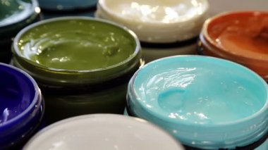 Çizmek hazırlanıyor. Yakın - yukarı çiçek ile bir kompozisyon tabloda o kürsüye farklı akrilik boya büyük bidon renkler.