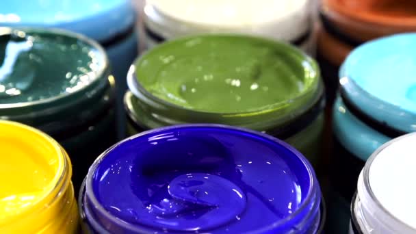 Preparing to draw. Large cans of acrylic paint in different colors, which are on the table in a composition with flowers. — Stock Video