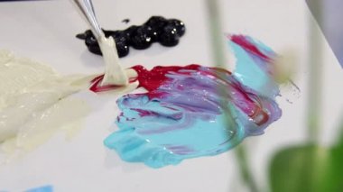 Sanatçı boya fırçası fildişi ve kırmızı renk paletindeki renkleri karıştırma için karışımları. Çizmek hazırlanıyor
