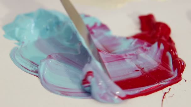 Malerspachtel zum Zeichnen, mischt blaue und rote Farbe in Nahaufnahme — Stockvideo