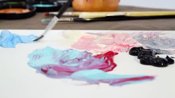 The artist draws a brush with blue paint from the Board for mixing colors and is preparing to paint a picture — Stock Video