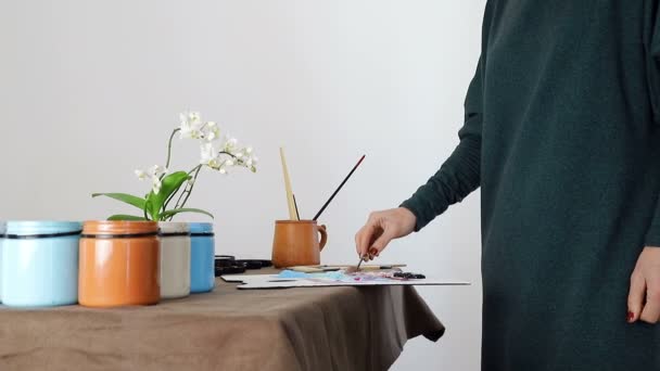 La mano femenina del artista, mezcla los colores en el tablero, y se prepara para pintar un cuadro con pinturas acrílicas — Vídeo de stock