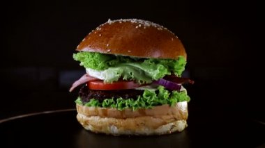 Hamburger, ahşap bir gemide bir pirzola ve omlet ve Yeşiller ile kaplı ile döner. Siyah arka plan üzerine