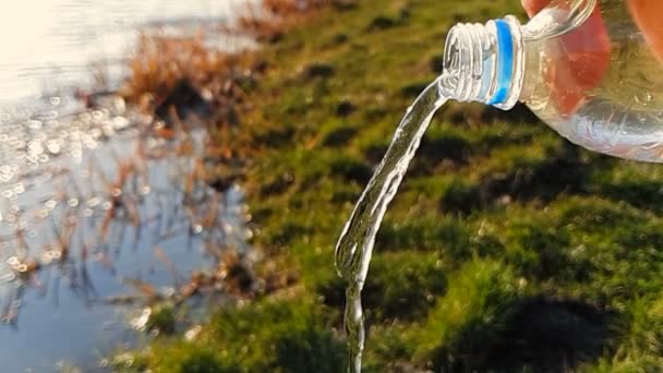 Primer plano del agua que fluye de una botella de plástico, sobre un fondo de hierba verde. 1000FPS cámara lenta — Vídeo de stock