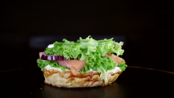 O pão cai sobre o hambúrguer em câmara lenta. Comida rápida. Delicioso hambúrguer no fundo preto — Vídeo de Stock