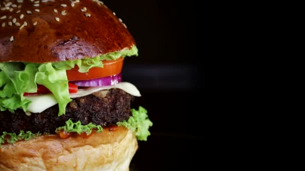 Hızlı yemek. Kırmızı biber ile Burger, yavaşça siyah bir arka planda ahşap bir tahta üzerinde iplik — Stok video