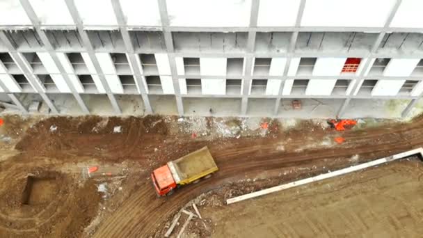 Die Aussicht von oben. Ein leerer Lastwagen fährt an unvollendeter Konstruktion vorbei. — Stockvideo