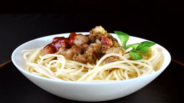 Pasta con carne y salsa, rotar en un plato de primer plano sobre un fondo negro — Vídeo de stock