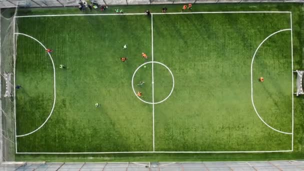 Група дітей, які грають у футбол на новому полі зі штучним дерном. Гравець забиває гол проти суперника — стокове відео