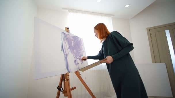 Mulher artista começa a pintar um quadro com uma espátula e tintas acrílicas. Criando um desenho sobre tela — Vídeo de Stock