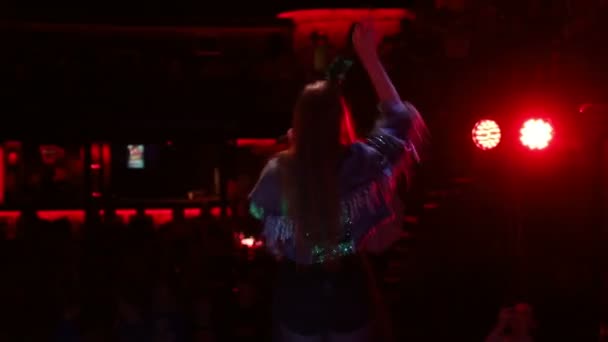 Κορίτσι που τραγουδάει και χορεύει στη σκηνή, πίσω όψη του τραγουδιστή. Φως και καπνός στη σκηνή. — Αρχείο Βίντεο