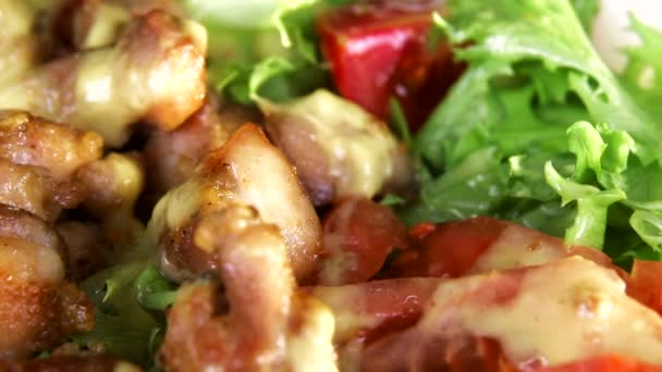 Yeşillik ve et parçaları ile salata, siyah bir arka plan yakın çekim üzerinde beyaz bir tabak içinde kendi ekseni etrafında döner — Stok video