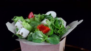 Sağlıklı beslenme. Salata yeşillik ve peynir domates ve salatalık dilimleri. Plaka yakın çekim siyah bir arka plan üzerinde döner