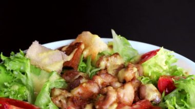 yeşillik ve et parçaları ile salata, siyah bir arka plan yakın çekim üzerinde beyaz bir tabak içinde kendi ekseni etrafında döner