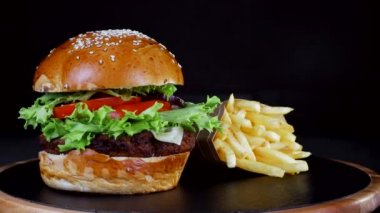 Fast food yemekleri. Berger patates kızartması ile, siyah arka plan üzerinde ahşap Kurulu spin