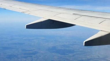 Uçağın penceresinden görüntüleyin. Mavi gökyüzü ve beyaz bulutlara karşı uçağın kanadı. Arka plan