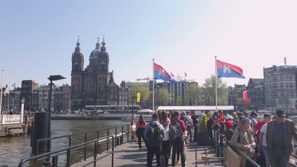 荷兰阿姆斯特丹。25.04.2019. 等待游艇的人排队。阿姆斯特丹的圣尼古拉斯大教堂是从运河的水域拍摄的。阿姆斯特丹 荷兰. — 图库视频影像
