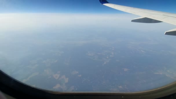 Vista dal finestrino dell'aereo. L'ala del velivolo contro il cielo blu e le nuvole bianche. Contesto — Video Stock