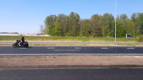 Twee fietsers op een motorfietstocht op de snelweg in Nederland. Uitzicht vanaf de zijruit van de auto op snelheid. — Stockvideo