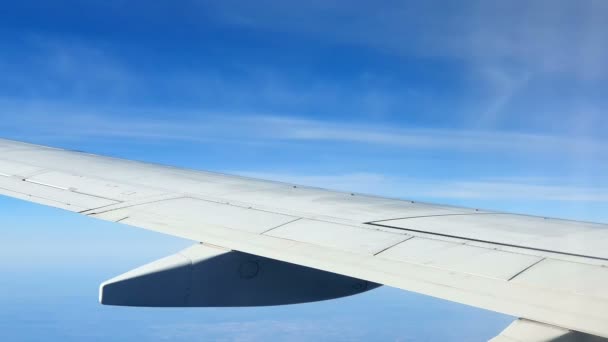 Blick aus dem Fenster des Flugzeugs. Die Tragfläche des Flugzeugs gegen den blauen Himmel und die weißen Wolken. Hintergrund — Stockvideo