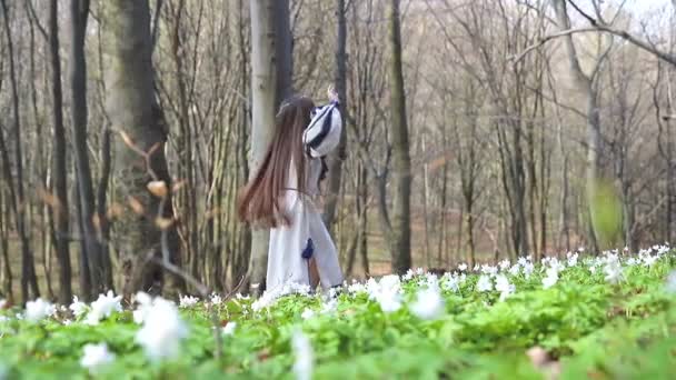 Linda niña dando vueltas en el parque alrededor de árboles y flores blancas del bosque — Vídeo de stock