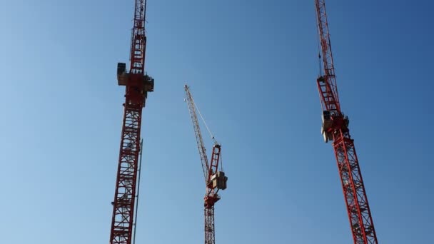 Tre gru da costruzione che stanno fianco a fianco contro il cielo blu senza nuvole. La vista dalla barca da diporto — Video Stock