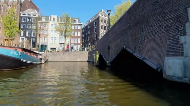 Amsterdam, Paesi Bassi. 25.04.2019. Vecchie navi parcheggiate nei canali di Amsterdam. Vista dalla barca tour. Girato con un obiettivo grandangolare — Video Stock