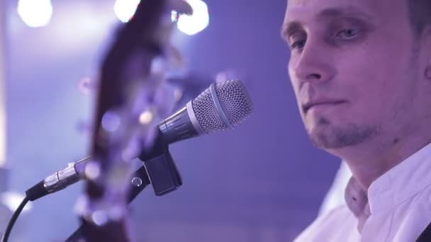 ミュージシャンの顔とマイクのクローズアップ。アーティストはステージ上でマイクに向かって歌う. — ストック動画