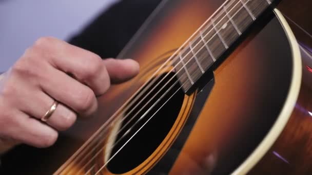 En man spelar en akustisk gitarr. Närbild av handen som träffar strängarna på gitarren — Stockvideo