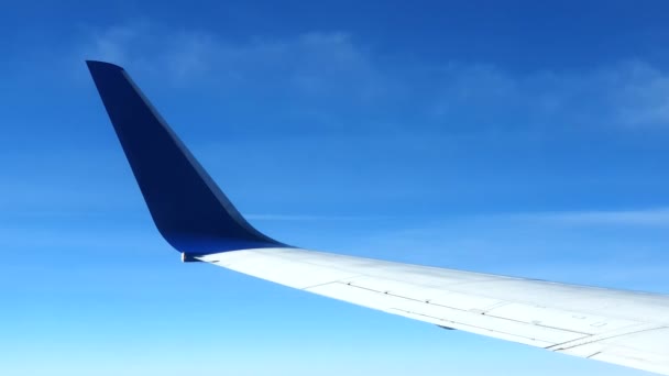 Blick aus dem Fenster des Flugzeugs. Die Tragfläche des Flugzeugs gegen den blauen Himmel und die weißen Wolken. Hintergrund — Stockvideo