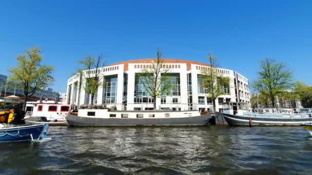 Амстердам, Нидерланды. 25июля 2019 года. Амстердамская национальная опера, дом, вид с прогулочной лодки на солнечный день. Выстрел на широкоугольном объективе — стоковое видео