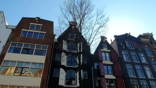 Magnifik arkitektur i Amsterdam hus. Husen lutas i olika riktningar. Fasaderna av husen i Amsterdam på en solig dag. Bländning av solen lyser in i kameran — Stockvideo
