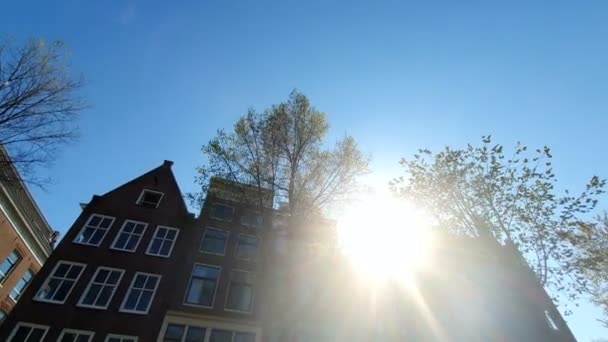 Magnifik arkitektur i Amsterdam hus. Husen lutas i olika riktningar. Fasaderna av husen i Amsterdam på en solig dag. Bländning av solen lyser in i kameran — Stockvideo